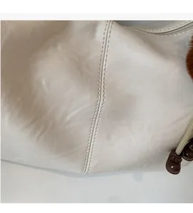 Detail view of cream leather shoulder bag featuring fine stitching and zipper hardware