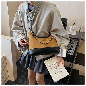 Detailed view of quilted suede crossbody bag with gold twist lock and metal chain strap