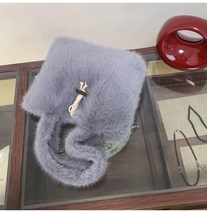 Detail der grauen Plüschtasche mit Holzknopfverschluss und weicher Kunstfellstruktur