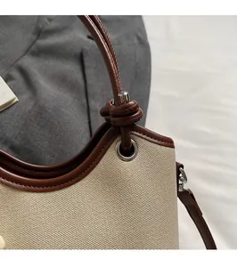 Gros plan d'un sac seau en toile avec finitions en cuir marron et coutures détaillées