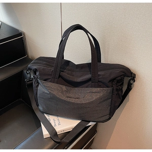 Detailed macro shot of the durable nylon fabric and grey checkered pocket on the travel tote