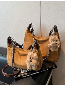Brown suede hobo bag set with chain strap and plush dog charm on studio background