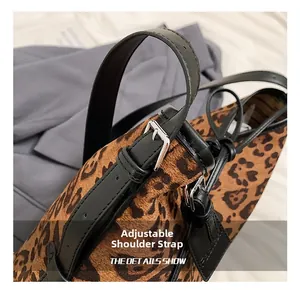 Detail of adjustable black leather shoulder strap with silver buckle on leopard print bag