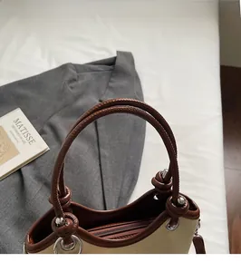 Détail du sac seau en toile avec poignées en cuir et fermeture éclair sur fond blanc neutre