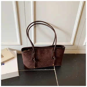 Detail of dark brown quilted suede shoulder bag with knotted straps and gold metal tips