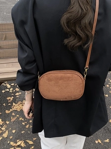 Brown frosted suede crossbody bag with gold hardware shown on person in autumn setting