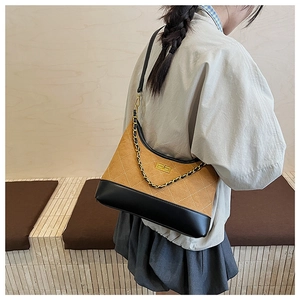 Detail of brown quilted faux suede handbag with black leather base and gold chain