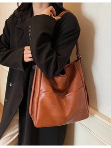 Brown leather tote bag with vintage large capacity worn with a black wool coat