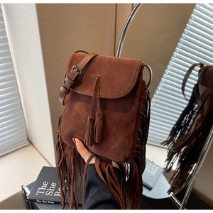 Détail d'un sac bandoulière bohème en daim marron foncé avec de longues franges et glands