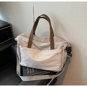 Detail of grey nylon travel tote featuring woven handles and fine textured zip pocket