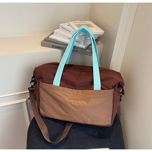 Detail view of large tote travel bag with sky blue handles and brown checked pocket