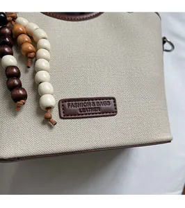 Détail de la texture toile beige avec garniture en cuir brun et perles décoratives