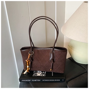 Detail of dark brown quilted suede tote bag with stylish wooden bead tassel charm