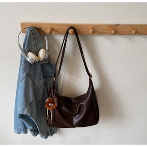 Deep brown large PU leather shoulder bag on a wooden hook with a cute plush charm