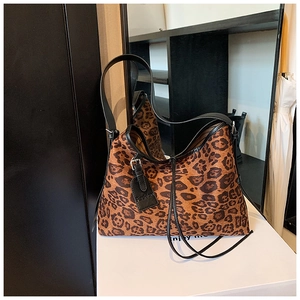 Detail of leopard print tote bag featuring a leather fashion tag and black shoulder straps