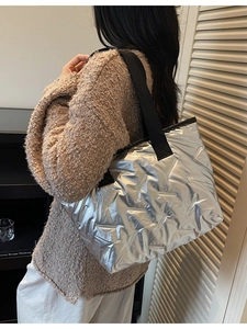 Quilted silver metallic tote bag with black strap shown in an autumn outfit context