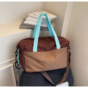 Detail of a brown plaid tote bag with light blue handles and a removable shoulder strap