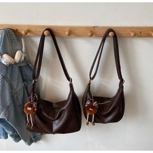 Detail of two sizes brown crescent shoulder bags with plush leopard bow charms
