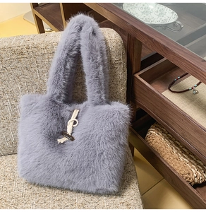 Detail der grauen Plüsch-Handtasche mit dekorativem Holzknebelknopf auf einem Sofa