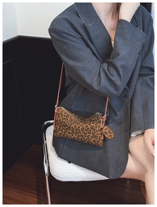 Detailed shot of leopard print crossbody bag with star charm worn with a grey blazer