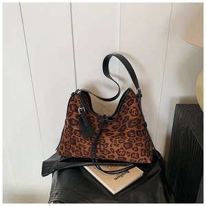 Detail view of leopard print hobo bag with black leather strap on a leather jacket