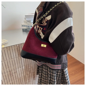 Detail of quilted burgundy suede bag with gold chain strap and metal turn-lock closure