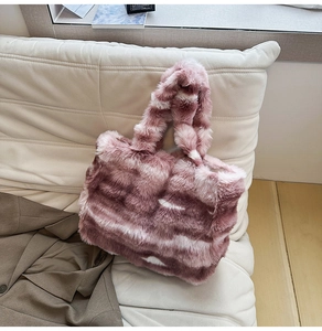 Détail de la texture d'un sac cabas en fausse fourrure rayée sur un canapé blanc doux