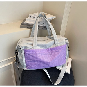 Detail of light gray nylon travel tote featuring a purple checkered pocket and adjustable strap