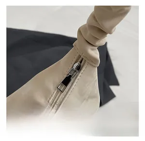 Close-up of beige leather bag featuring scrunched handle and silver metal zipper detail