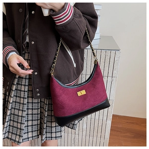 Detail of burgundy quilted suede chain bag featuring a golden rectangular twist lock