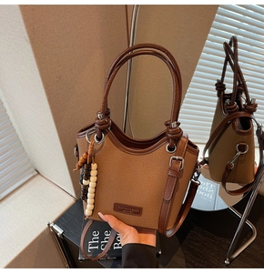 Vue détaillée du sac seau en toile marron avec anses en cuir et breloque en perles