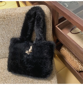 Detailansicht der schwarzen Plüschtasche mit cremefarbenem Seilknoten und Holzknopfverschluss