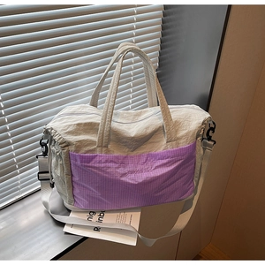 Close-up of water-resistant gray nylon fabric and purple plaid zipper pocket on tote bag