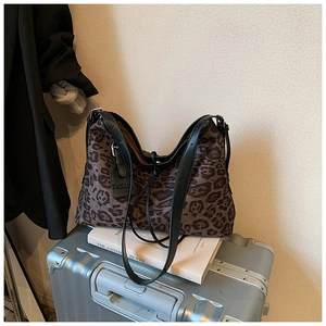Close-up of leopard print tote bag with black leather strap on a silver suitcase