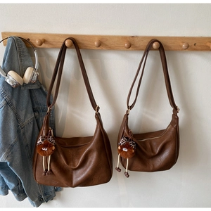 Detail of vintage brown leather crescent bags with leopard plush charms on a wall hook