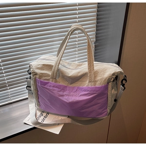 Detail of grey nylon travel tote featuring a purple plaid pocket and adjustable strap