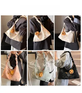 Detail view of stylish pleated hobo bag with teddy bear charm and elegant embroidery