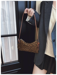 Close-up of leopard print crossbody bag featuring a zipper and brown leather strap