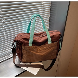 Detail of nylon travel tote with mint green handles and brown mesh pocket