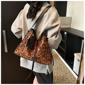 Detail of leopard print tote bag with black leather shoulder strap and fashion tag