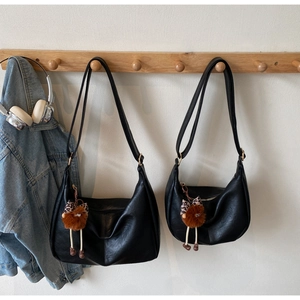 Detail view of black dumpling shoulder bags in two sizes with plush bear charms