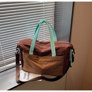 Detail of coffee nylon travel tote bag with khaki plaid pocket and contrast green straps