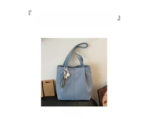 Detail of blue canvas tote bag featuring large capacity and stylish alphabet pompom charm