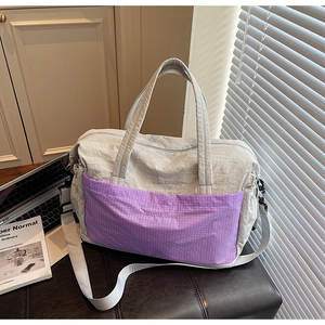 Detail of grey travel tote bag featuring purple plaid pocket and nylon texture