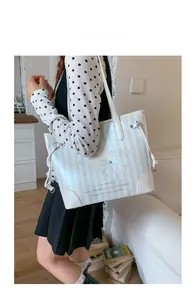 Détail du sac cabas rayé avec motif de coquillage et renforts en cuir blanc