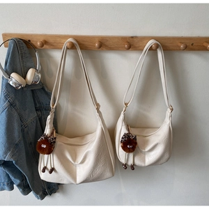 Detail of off-white dumpling bags in large and small sizes with furry monster charms