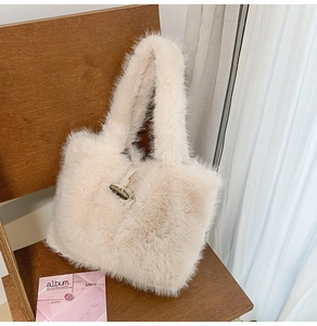 Detail einer Plüschhandtasche aus beigem Kunstfell mit Knebelverschluss auf Holzstuhl