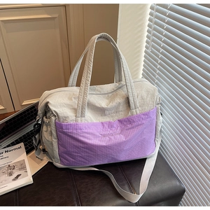 Detail of grey nylon travel tote with purple plaid front pocket and adjustable shoulder strap
