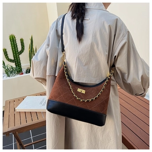Detail of rhombic quilted stitching and gold chain strap on a suede crossbody bag