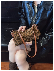 Close-up of leopard print shoulder bag with brown leather strap and side pendant